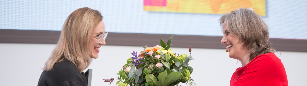 Jurorin Insa Wilke überreicht der Gewinnerin Barbi Marković einen Blumenstrauß am Rednerpult bei der Verleihung vom Preis der Leipziger Buchmesse 2024 Jurorin Insa Wilke überreicht der Gewinnerin Barbi Marković einen Blumenstrauß am Rednerpult bei der Verleihung vom Preis der Leipziger Buchmesse 2024
